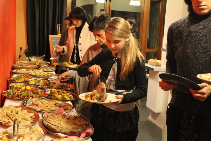 Eine junge Frau, die eine Mahlzeit in einem Agriturismo teilt, umgeben von typischen Gerichten und einer einladenden Atmosphäre.