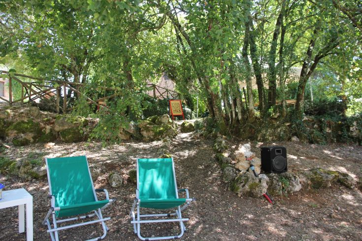 Zwei grüne Liegen in einer natürlichen Umgebung, umgeben von Bäumen und Felsen.