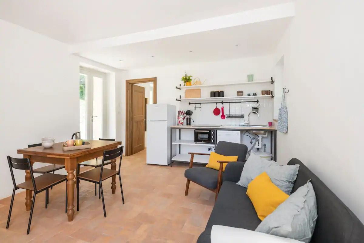 A bright living room with an open kitchen, wooden table, and contemporary decorations.