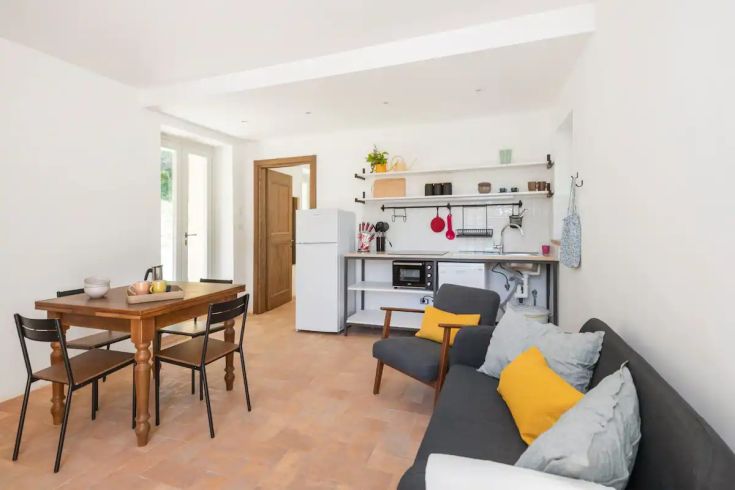 Un salon lumineux avec une cuisine ouverte, une table en bois et des décorations contemporaines.