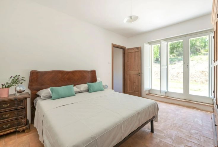 Chambre double simple avec lits et fenêtres donnant sur un paysage naturel.