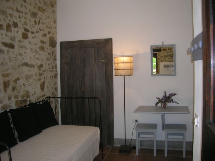 Un'accogliente camera in un agriturismo caratterizzato da pareti in pietra e affacciata su un bel panorama.