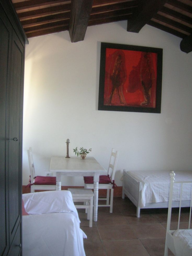 Un soggiorno confortevole con mobili bianchi, un tavolo da pranzo e decorazioni in tonalità rosse.