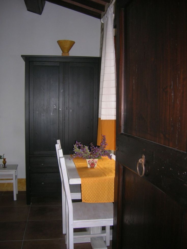Interno di un agriturismo con tavolo, fiori freschi e armadio in legno chiaro.