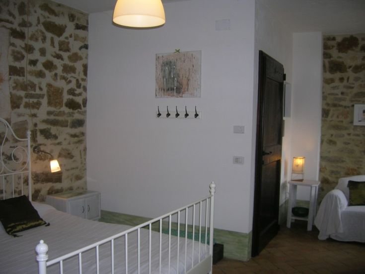 Camera semplice con elementi in pietra e decorazioni rustiche che creano un'atmosfera calda.