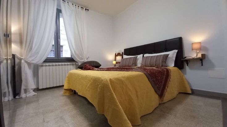 Camera luminosa con letto matrimoniale e arredamento essenziale, adatta a un soggiorno sereno.