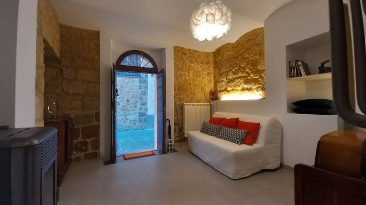 Soggiorno semplice con dettagli in pietra, dotato di una porta che conduce a uno spazio esterno.