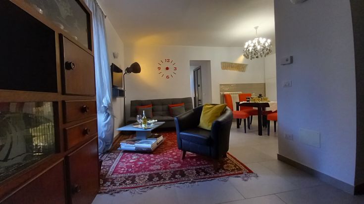 Spazioso soggiorno con un divano, lampada semplice e un tavolo pronto per gli ospiti.