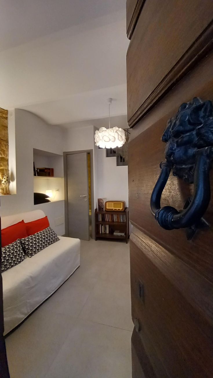 Soggiorno contemporaneo con divano comodo e decorazioni sobrie, illuminato da una lampada dal design semplice.