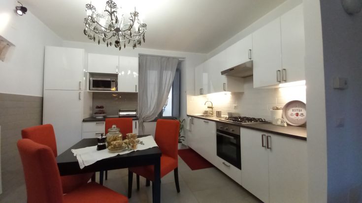 Cucina semplice e ben organizzata, con tavolo e sedie rosse. Ambiente pratico e piacevole.