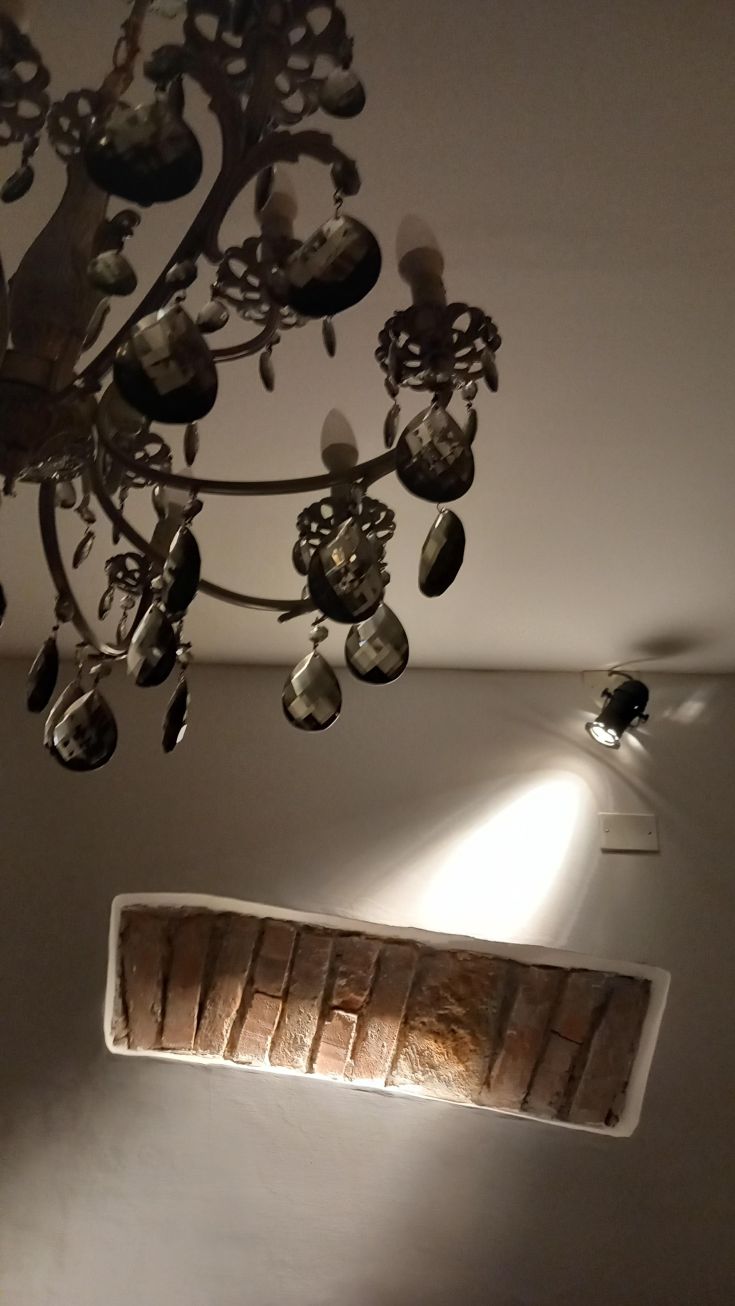 Lampadario semplice e parete in mattoni, spazi luminosi e accoglienti.