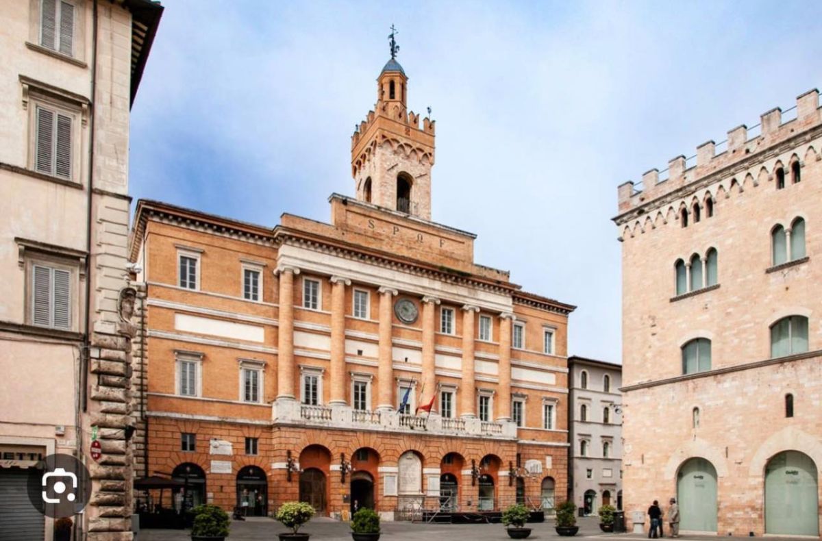 Un palazzo con torre nella piazza principale di Foligno, caratterizzato da stile architettonico tradizionale.
