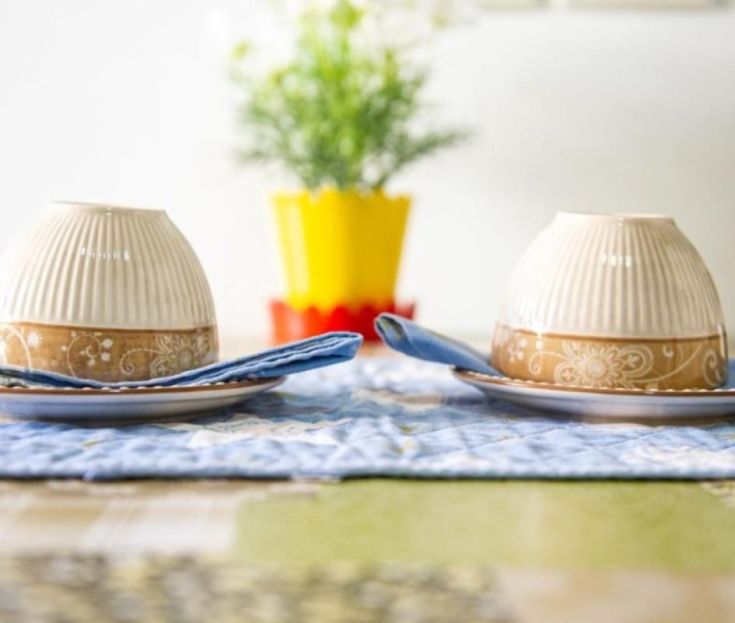 Ein gut gedeckter Tisch mit Tellern, Schalen und Servietten in einer gemütlichen und informellen Umgebung.