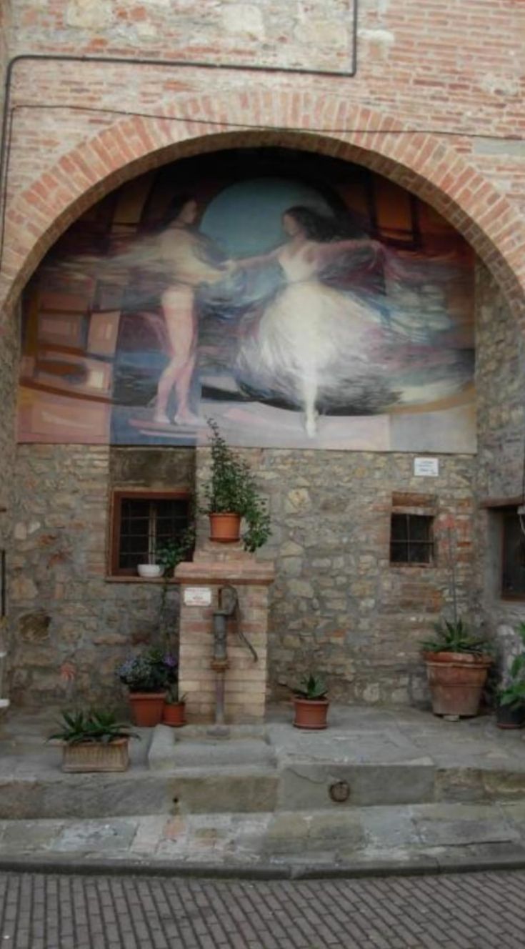 Ein Wandgemälde, das zwei tanzende Figuren darstellt, umgeben von einem Backbogen in einem schlichten Umfeld.