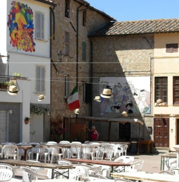 Eine typische Ecke eines italienischen Dorfes mit Statuen, Flaggen und dekorativen Hüten.