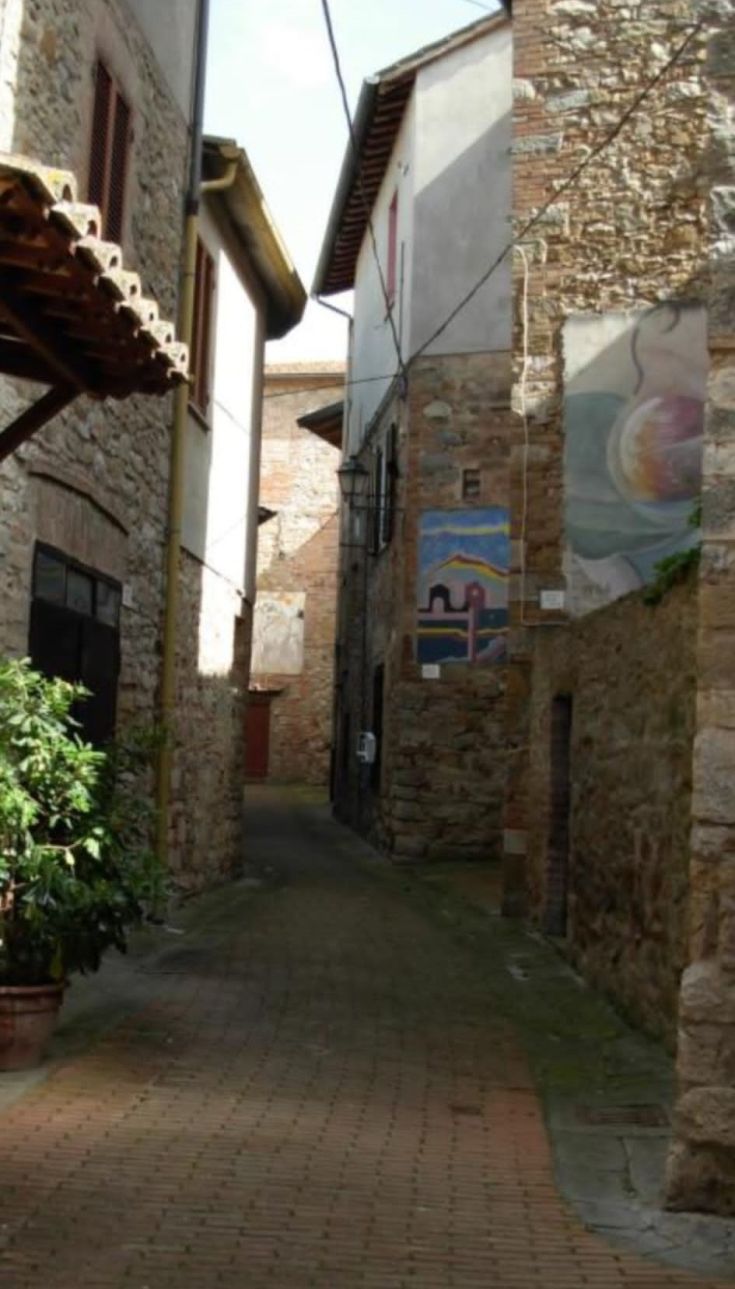 Eine engesteinstraße in Mugnano, umgeben von Steingebäuden und Wanddekorationen, mit historischer Atmosphäre.