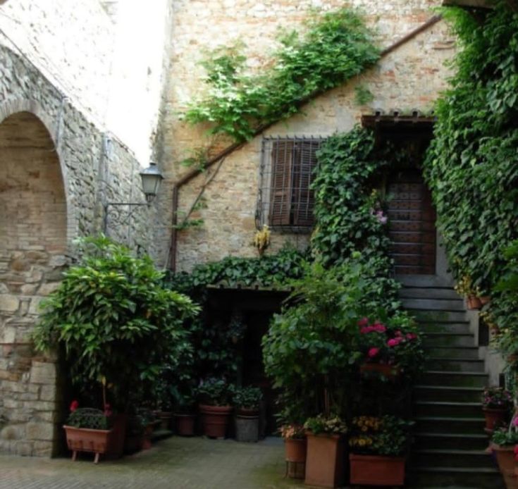 Ein ruhiger Bereich eines historischen Dorfes, der einige Bäume und mittelalterliche Architektur aufweist.