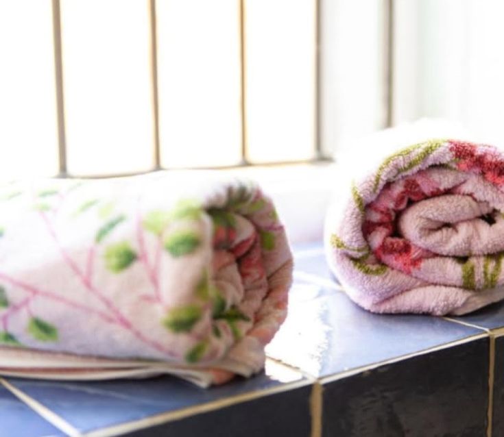 Gerollte Handtücher ordentlich auf einem Regal in einer hellen und einladenden Umgebung angeordnet.