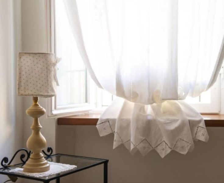 Details eines hellen Raums mit weißen Vorhängen und einer Lampe. Der Raum ist einfach und gepflegt.