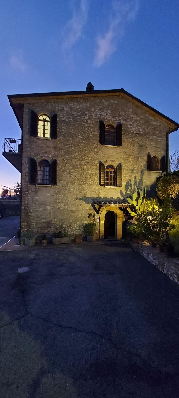 Un edificio in pietra illuminato al crepuscolo, immerso nella vegetazione, che genera un'atmosfera suggestiva.