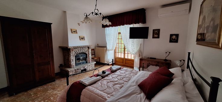 Camera semplice con dettagli rustici che offre comfort moderni, affacciata su un'area verde.