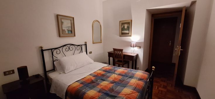 Una camera con letto singolo, arredamento sobrio e dettagli discreti.