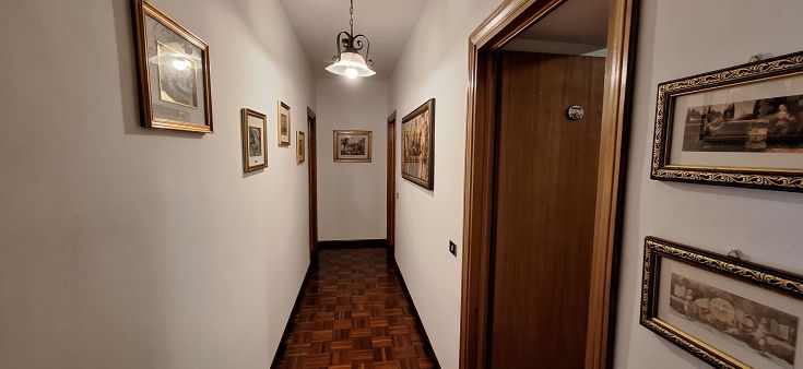 Un corridoio luminoso, arredato con alcune cornici e decorazioni semplici, che crea un'atmosfera invitante.