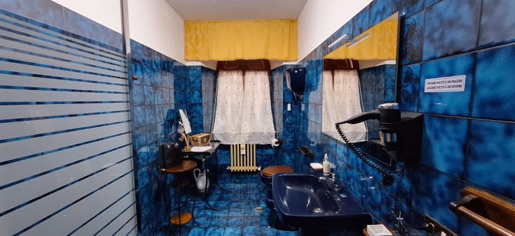 Bagno con piastrelle blu e mobili in legno, ben illuminato e con un'atmosfera accogliente.