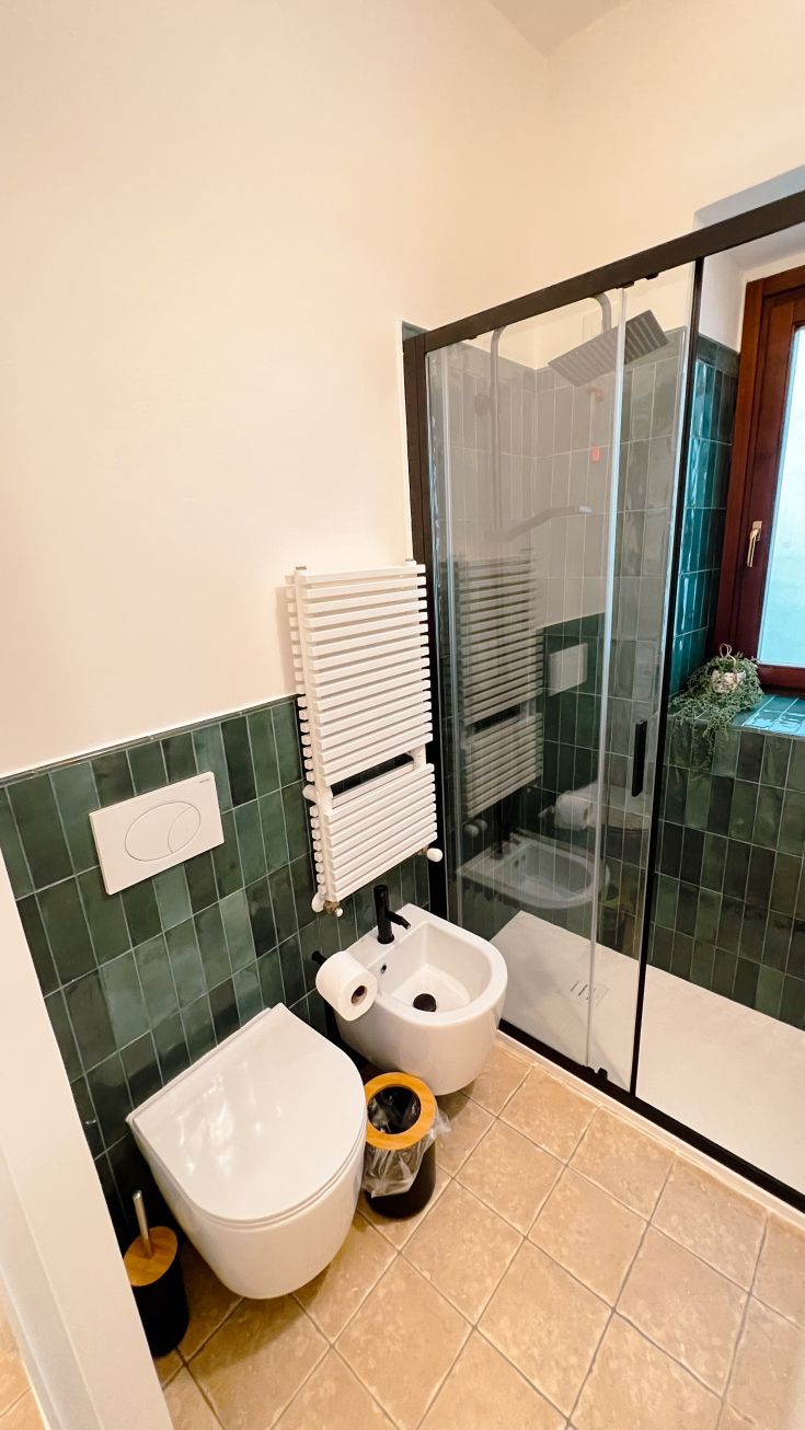 Zeitgemäßes Badezimmer mit grünen Fliesen und einer Dusche. Ein funktionaler und moderner Raum.