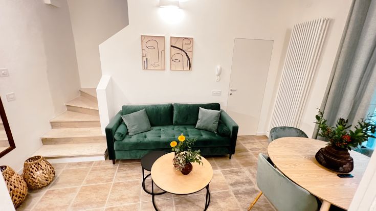 Einfaches Wohnzimmer mit einem grünen Sofa und modernen Dekorationselementen, ideal für Entspannungsmomente.