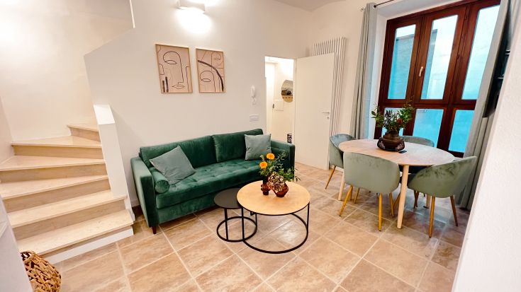 Ein geräumiges Wohnzimmer mit einem grünen Sofa und einem großen Esstisch. Helle und zeitgenössische Atmosphäre.