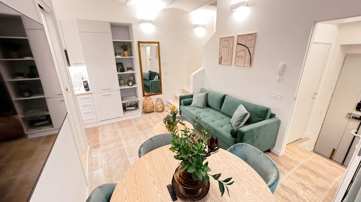 Ein einfacher Wohnraum mit grüner Couch und Holztisch. Perfekt zum Entspannen.