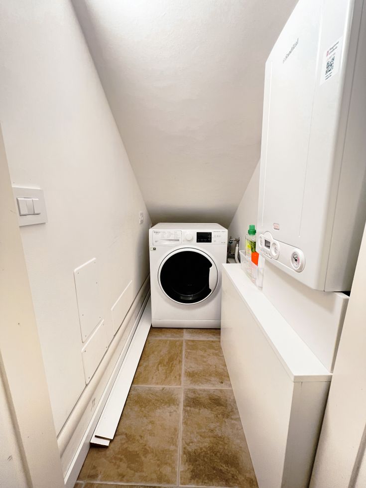 Ein funktionaler Waschraum mit Waschmaschine und Abstellbereichen, ideal für den täglichen Gebrauch.