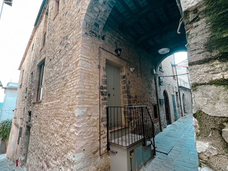 Eine steinerne Treppe führt zum Eingang eines alten Gebäudes. Die Architektur ist einfach und funktional.