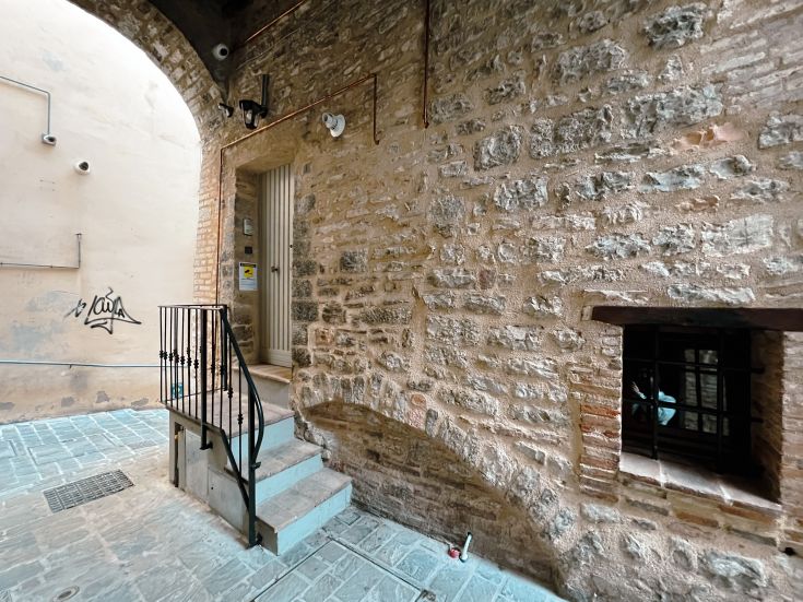 Der Eingang eines Backsteingebäudes mit einer Treppe, die zu den oberen Etagen führt, gut beleuchtet.