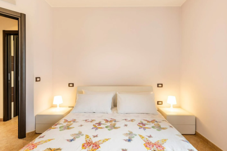 Camera semplice con letto matrimoniale e decorazioni floreali, perfetta per un soggiorno tranquillo.