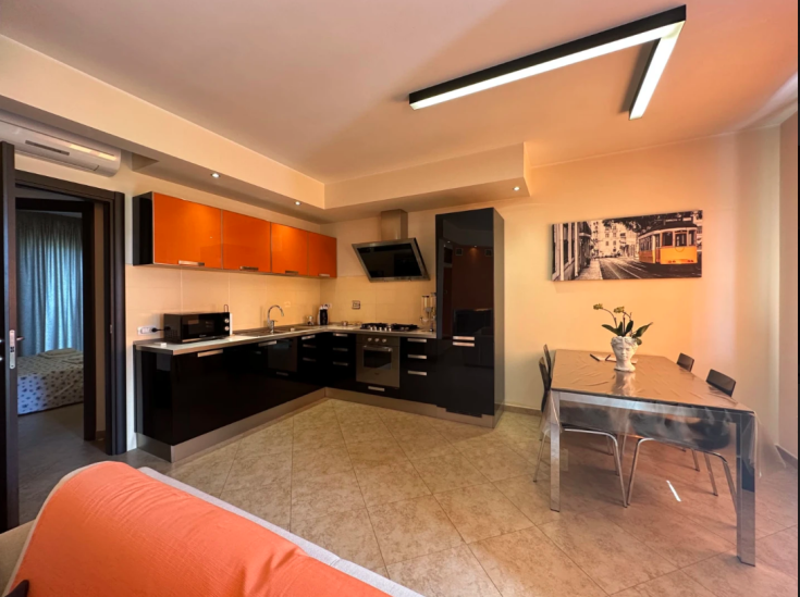 Cucina moderna con area pranzo ampia, dotata di elettrodomestici funzionali e decorazioni semplici.