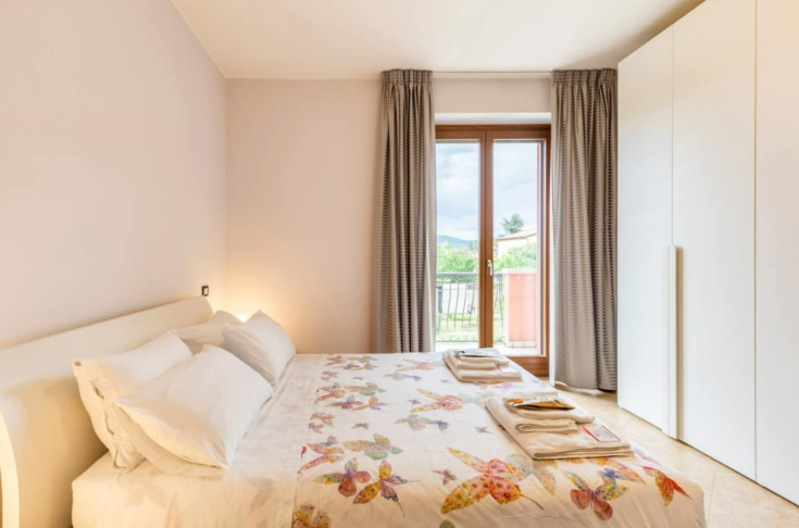 Camera da letto spaziosa e ben illuminata, con letto matrimoniale e semplici decorazioni floreali, adatta per momenti di relax.
