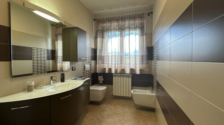 Bagno contemporaneo con colori caldi, arredato con comfort. Presenta ampie finestre che illuminano l'ambiente.