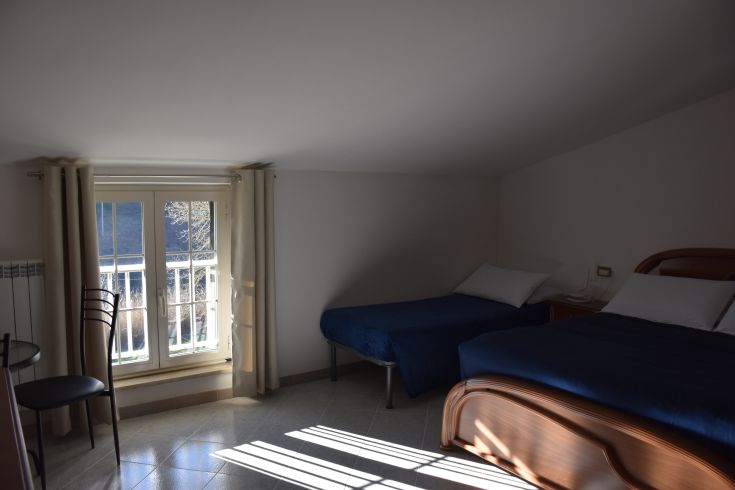 Chambre spacieuse du B&B avec lits simples et vue sur le paysage environnant.