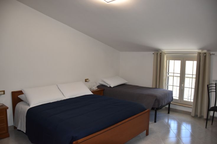 Chambre spacieuse et confortable avec un lit double et un lit simple, bien éclairée par la fenêtre.