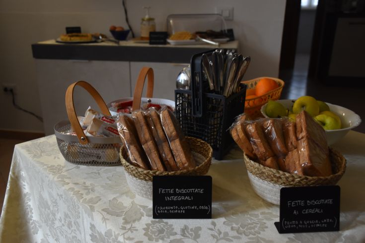 Petit-déjeuner au B&B avec des tartines de pain complet, des fruits frais et un assortiment de pâtisseries.