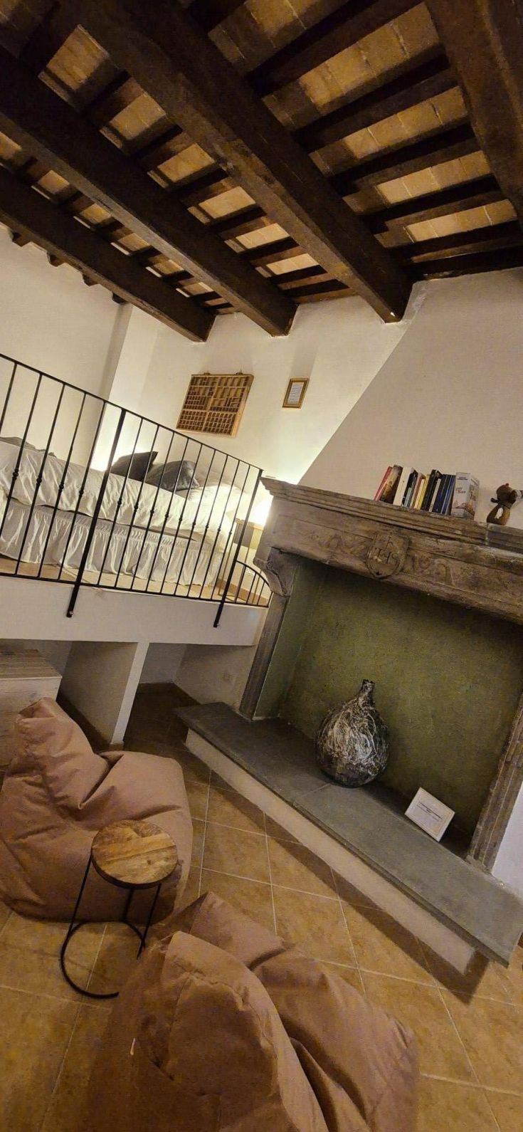 Soggiorno semplice con soppalco, camino e elementi rustici che creano un'atmosfera confortevole.