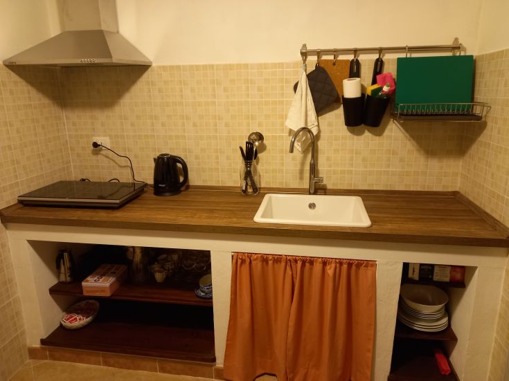 Cucina funzionale dotata di piano cottura, lavello e ripiani in legno chiaro, con un'atmosfera accogliente.