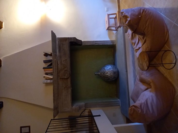 Un soggiorno confortevole con un camino, pouf e semplici decorazioni. Luogo adatto per momenti di relax.