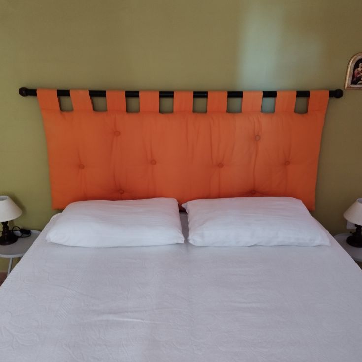 Letto semplice con testiera arancione, adatto per un ambiente confortevole.