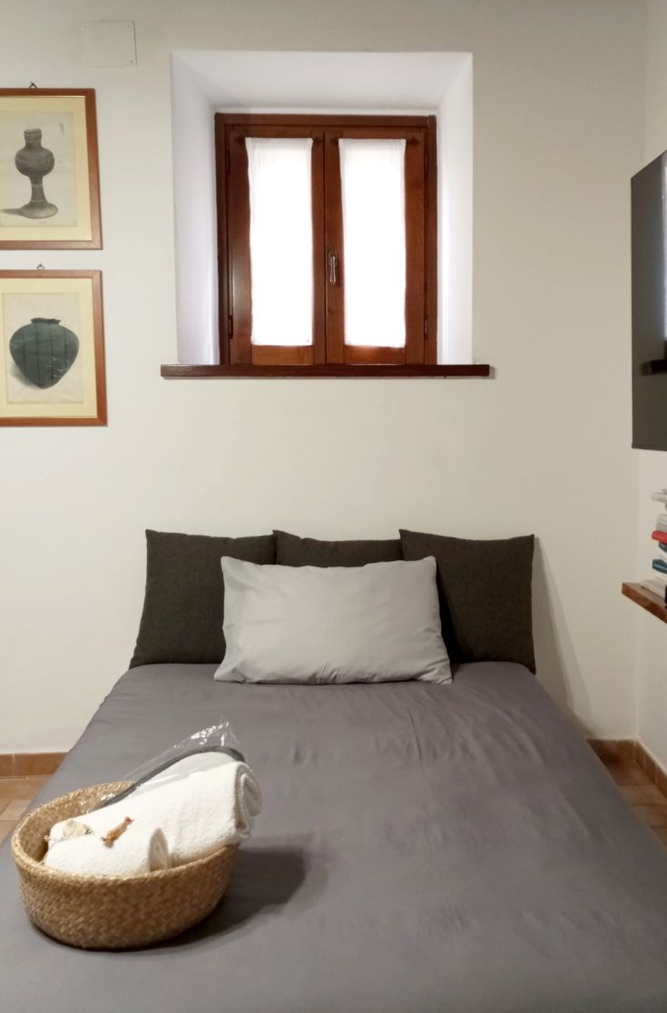 Einfaches Zimmer mit einem Bett und rustikalen Dekorationen, ideal für entspannende Momente.