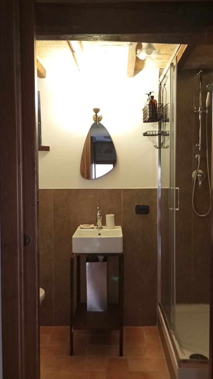 Moderne Badezimmer mit Waschbecken und Dusche, geprägt von warmen Tönen und Holzausstattungen.