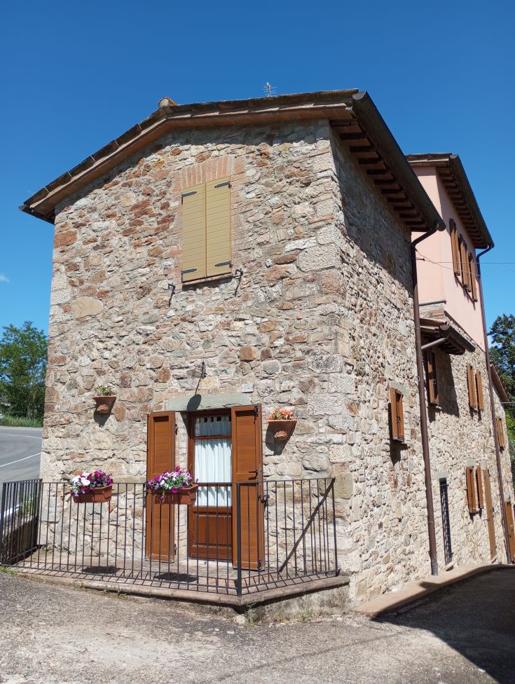 Ein Steinhaus inmitten der Natur, mit bunten Blumen an den Fenstern.