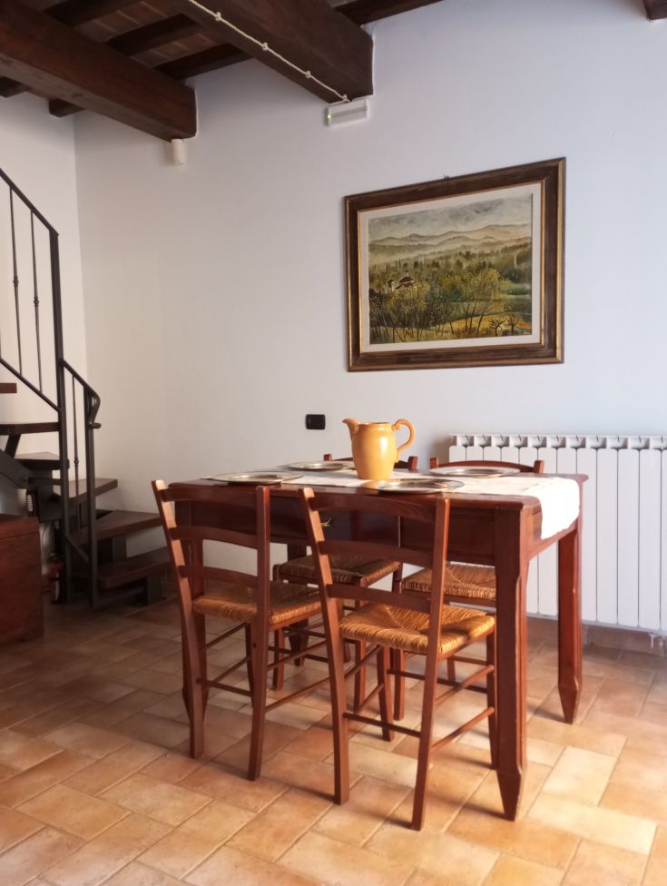 Ein rustikales Wohnzimmer auf dem Land mit einem Holztisch und Stühlen, umgeben von der friedlichen Landschaft der Umbrien.